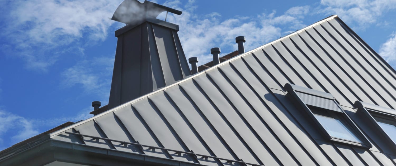 Modernes Stehfalz-Metalldach mit Dachfenster, Schneefang, Dachrinne, Dunstabzügen und mit Metall verkleidetem Schornstein