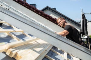 Dachdecker arbeitet konzentriert an Holzkonstruktion auf dem Dach