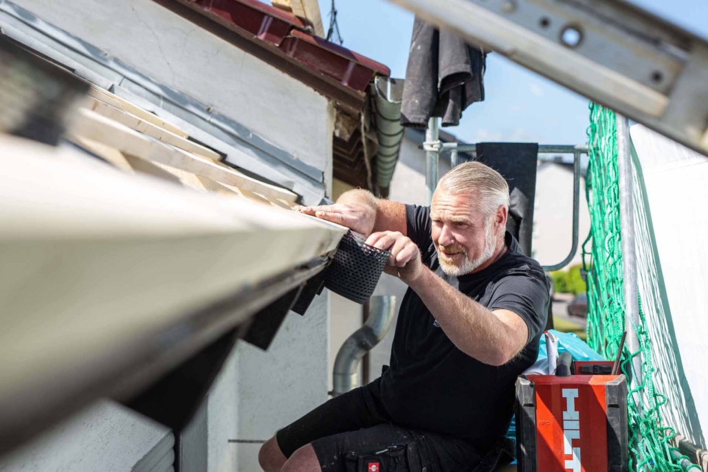 Mann arbeitet an Dachrinne mit Gittereinsatz