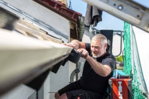 Mann arbeitet an Dachrinne mit Gittereinsatz