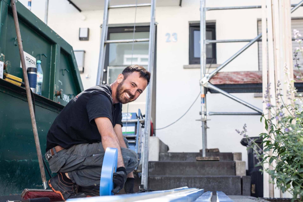 Handwerker arbeitet mit Klebeband auf Baustelle vor Haus