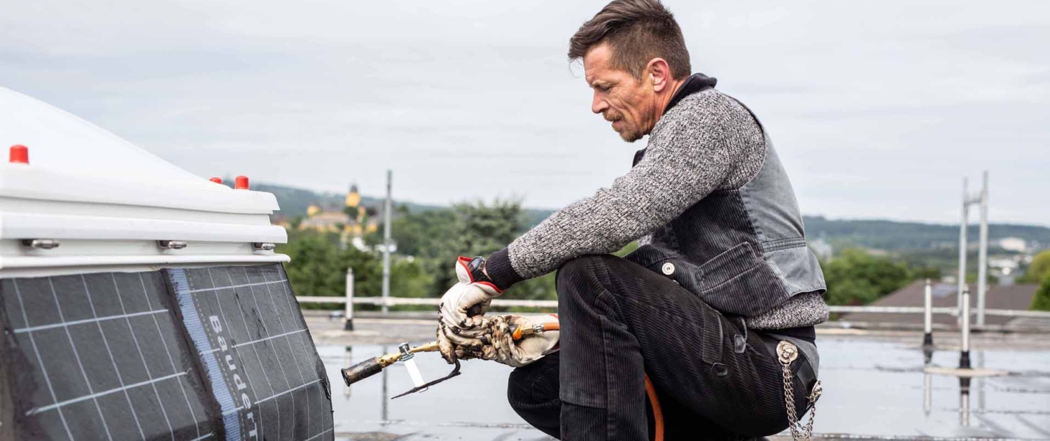 Flachdach-Abdichtung mit Brenner Dachdecker führt Abdichtungsarbeiten mit Gasbrenner aus