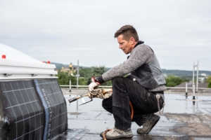 Dachdecker führt Abdichtungsarbeiten mit Gasbrenner aus