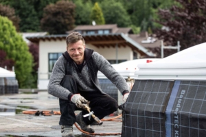 Dachdecker arbeitet lachend mit Brenner auf nasser Dachfläche