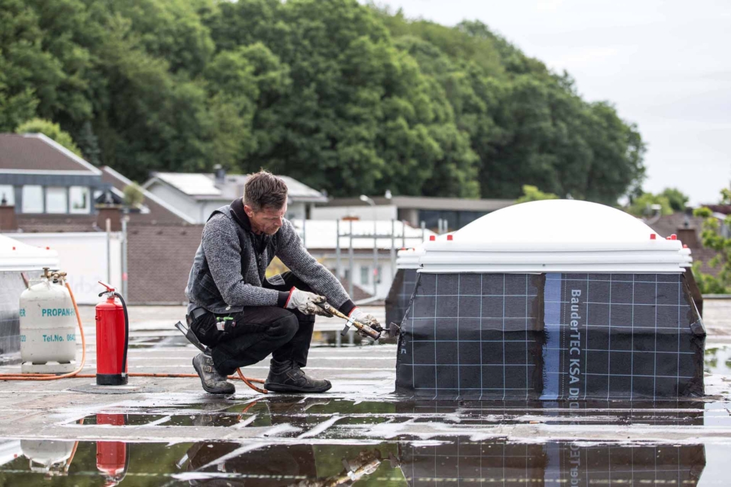 Dachdecker arbeitet mit Gasbrenner an Lichtkuppel