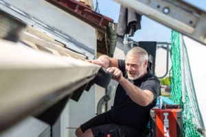 Mann arbeitet an Dachrinne mit Gittereinsatz