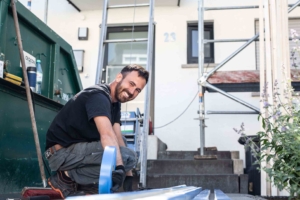 Handwerker arbeitet mit Klebeband auf Baustelle vor Haus