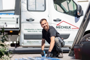 Dachdecker arbeitet vor Firmenfahrzeug an Profilblechen